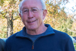 A man in glasses wearing a blue sweater