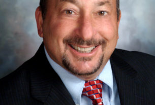 Frank Friedman smiles at the camera while wearing a suit