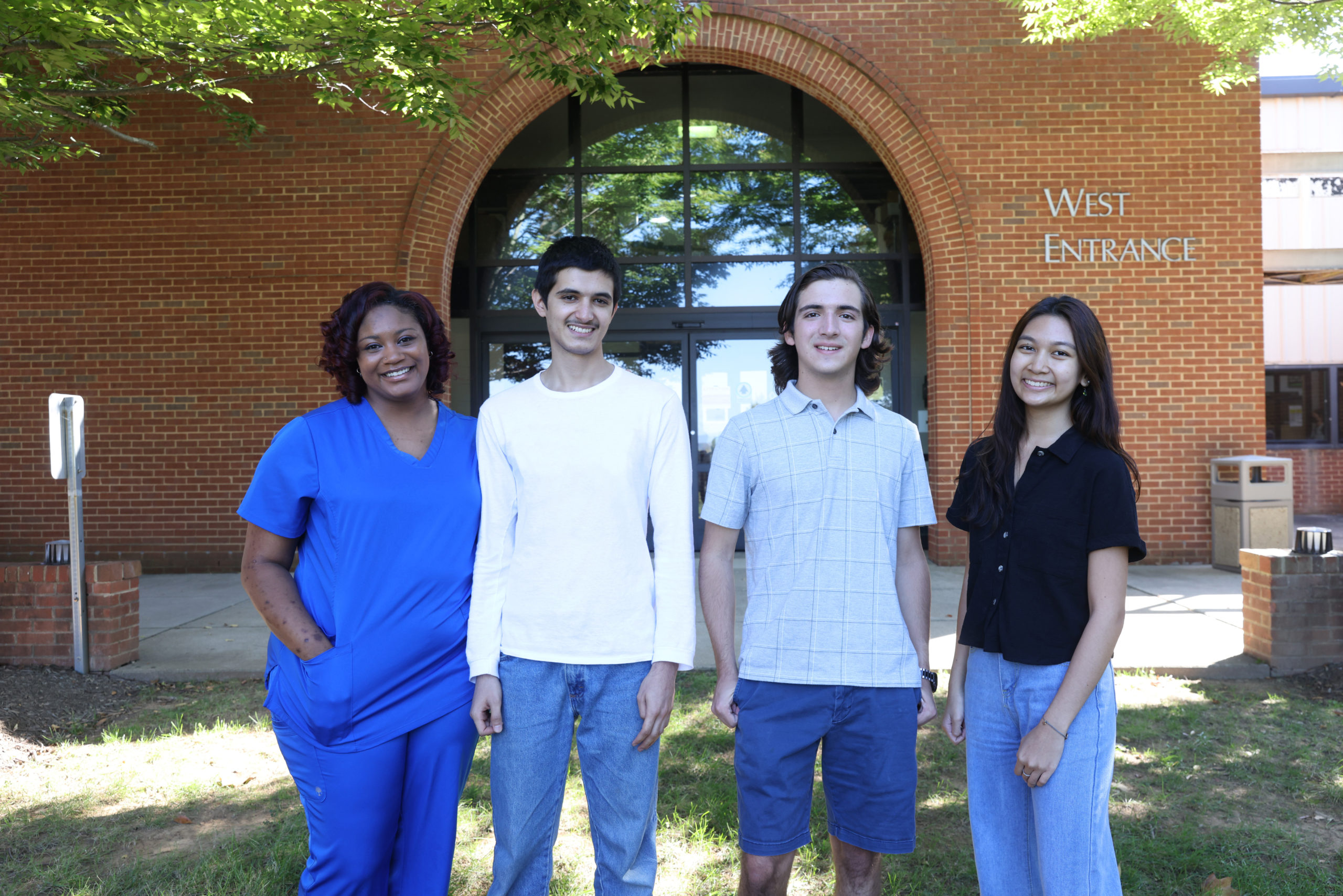 posed group of four students in front of the West Entrance to PVCC's main building