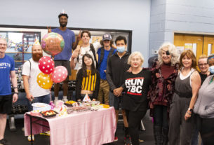 Students gather around a table with birthday cake and balloons.