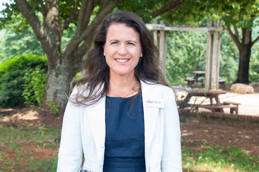 A woman with brown hair wearing a white jacket stands on the PVCC patio.