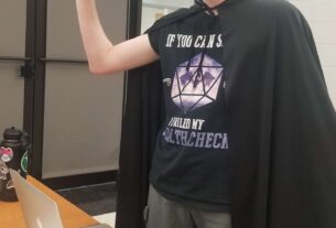 Benjamin Marcus at game table in black cloak and D&D shirt.