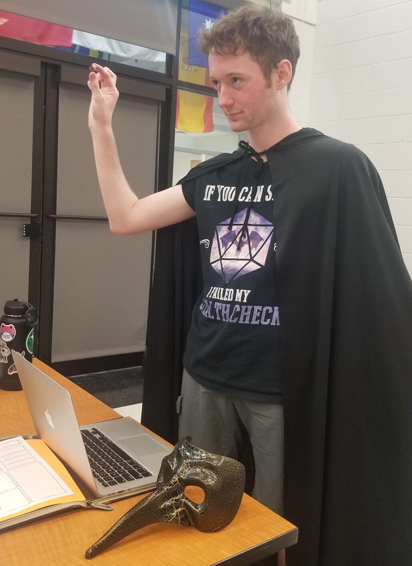 Benjamin Marcus at game table in black cloak and D&D shirt.