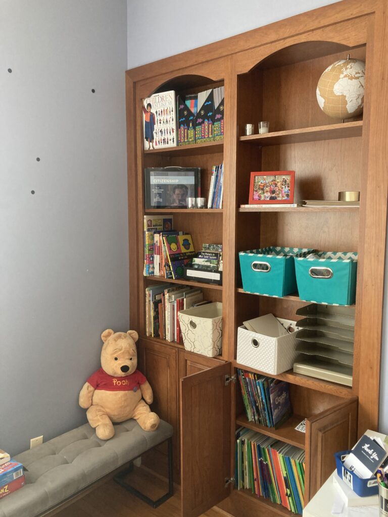 A corner of IN’s homey office, with a bookcase of children's books and a stuffed Winnie the Pooh bear. 