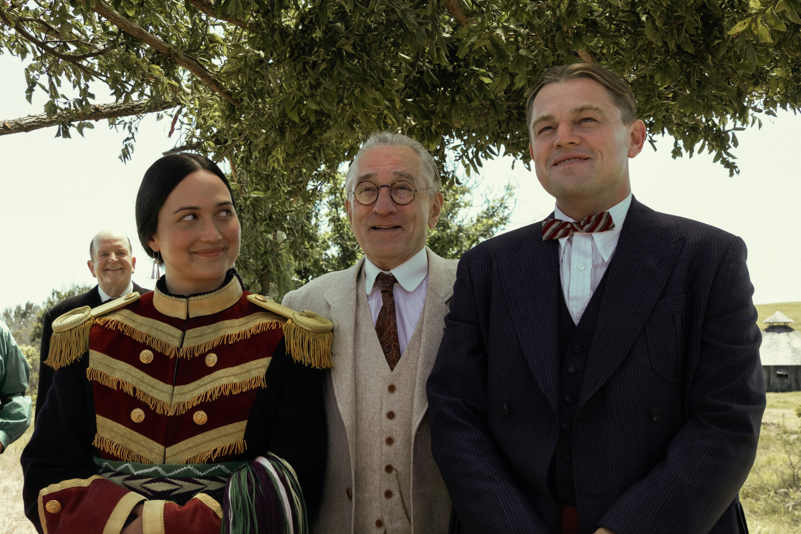 Robert De Niro stands behind Lily Gladstone, and Leonardo DiCaprio in “Killers of the Flower Moon.”