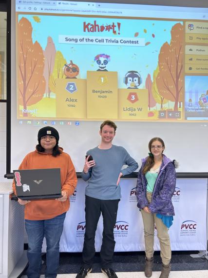 The trivia contest winners stand beneath the Kahoot! screen.