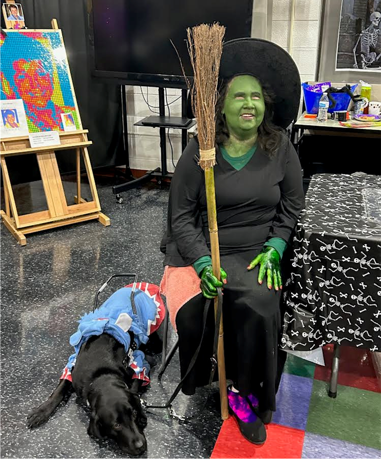 Adviser Sandra Bullins dressed up as a witch with her service dog beside her.