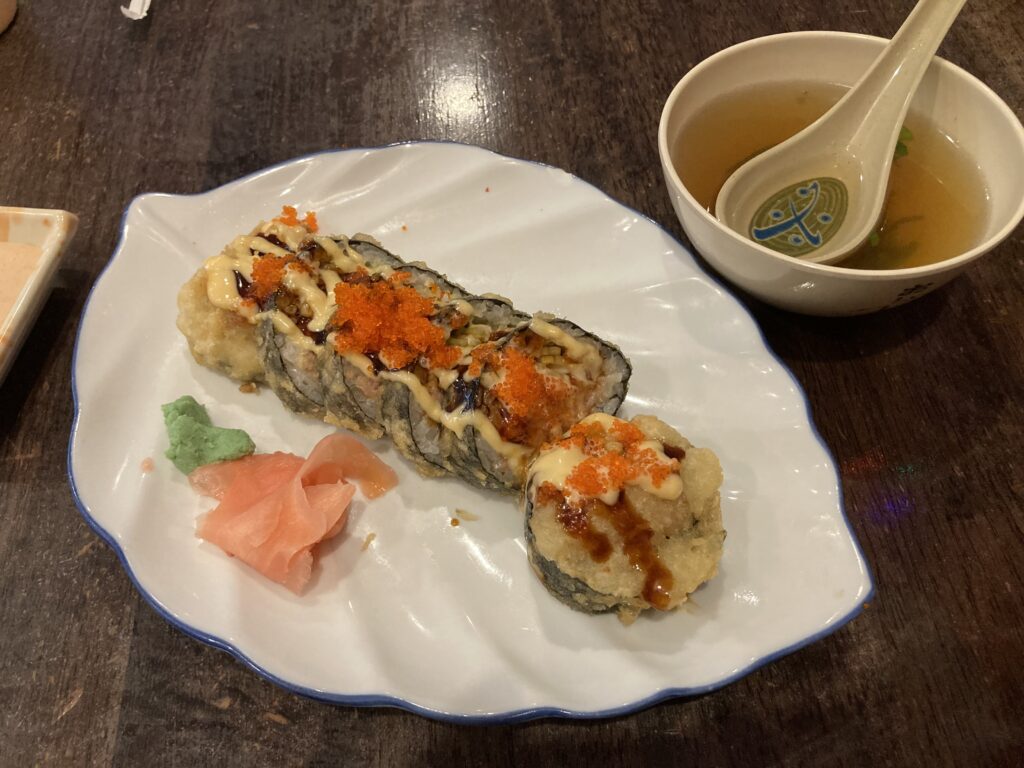 Sushi roll on a leaf-shaped plate with house soup beside.