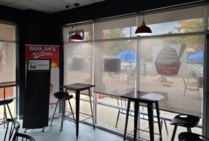 Bar stools in front of a large floor to ceiling window in the ice cream shop