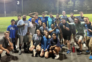 Chi Alpha members pose in a group shot in front of a field.