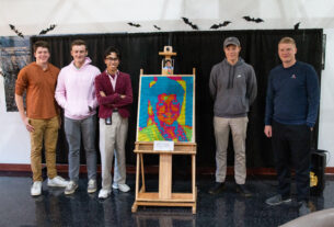 Members of the math club pose around the Rubik's cube portrait of Dr. Jean Runyon.