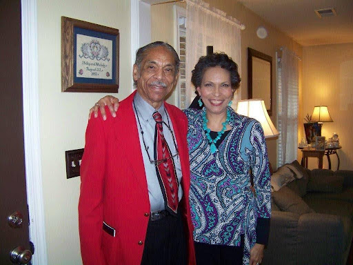 A man in a red jacket and Melody Day in a blue top smile for the camera