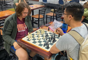 Two students sit at a table in the Bolick Student Center playing chess.