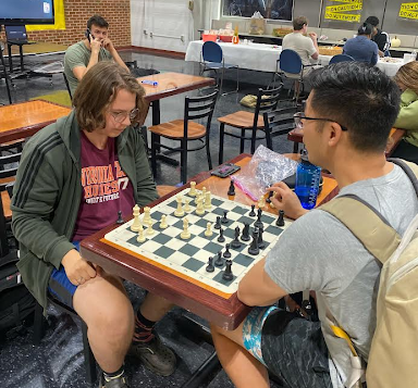 Two students sit at a table in the Bolick Student Center playing chess.