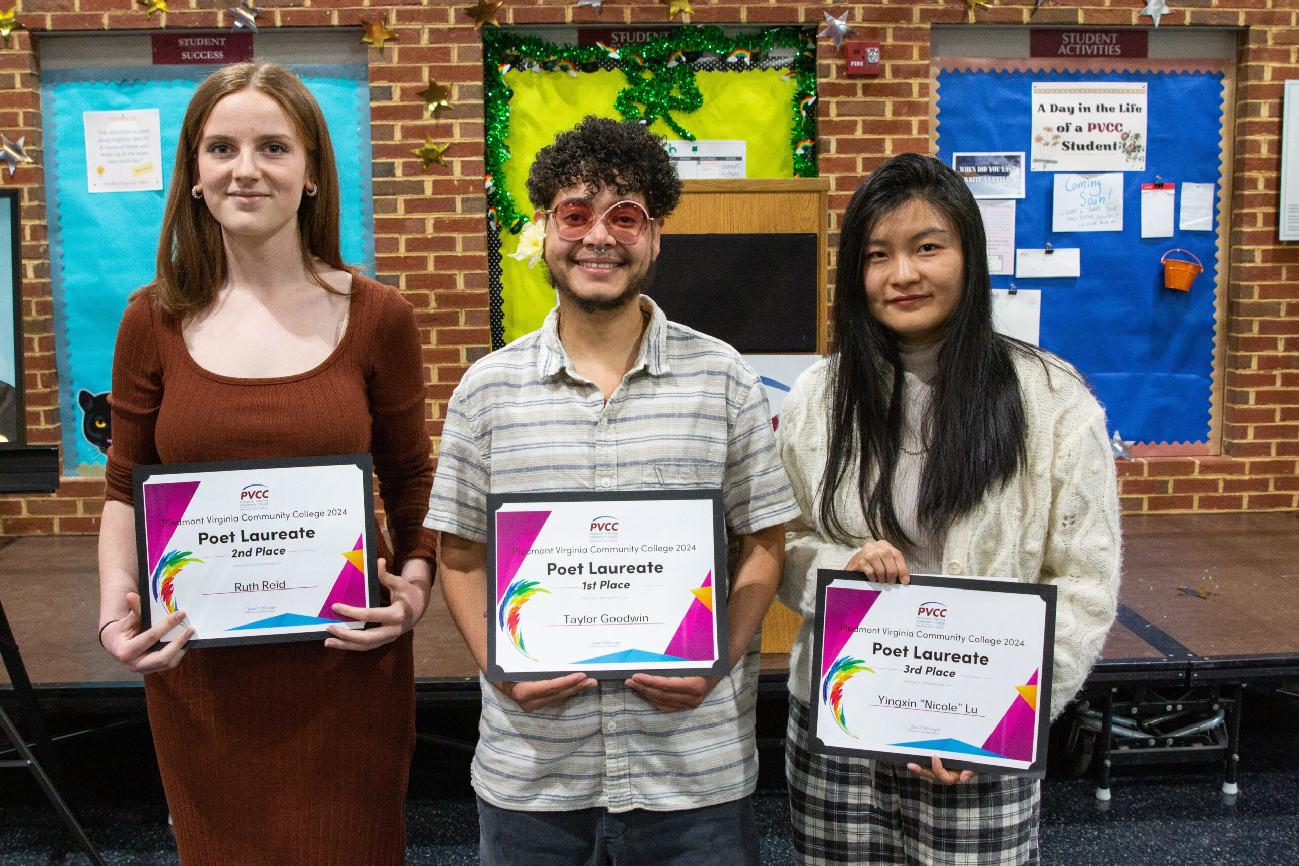 The three winners of the Poet Laureate standing in front of a stage.