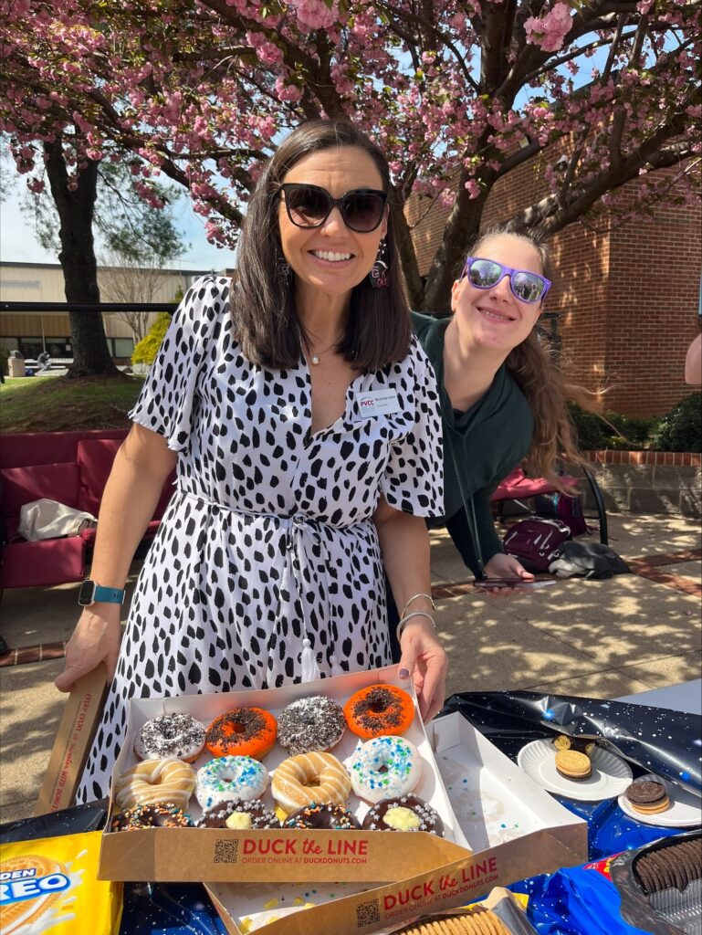 Coordinator of Student Engagement Mary-Evelyn Sellars and a student stand with a dozen donuts from Duck Donuts