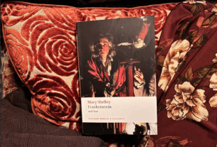 The Oxford Classics edition of Frankenstein sits against red pillows.