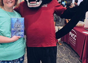 A woman holding a book next to a person in a Panther mascot costume