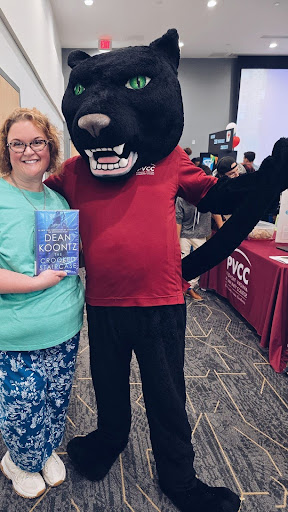 A woman holding a book next to a person in a Panther mascot costume