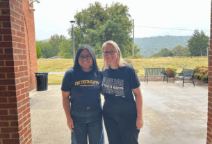 Two students wearing PTK shirts pose at the South Entrance to PVCC