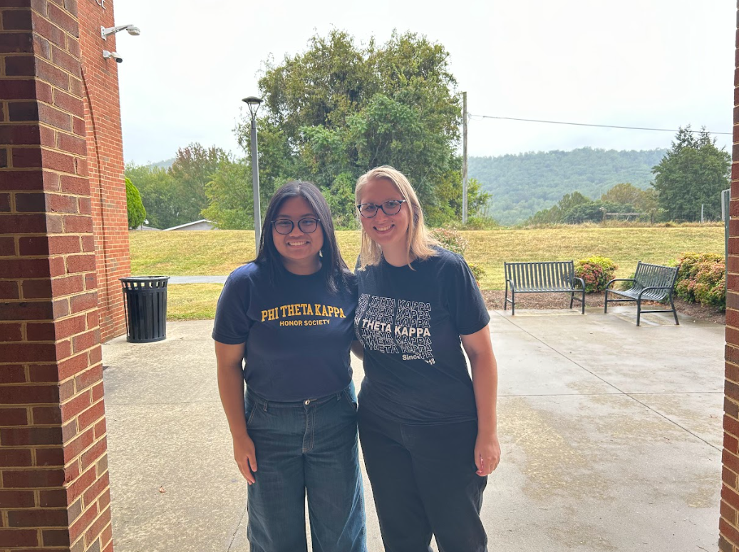Two students wearing PTK shirts pose at the South Entrance to PVCC