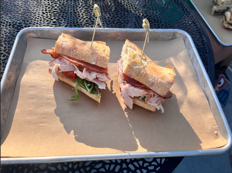 A turkey sandwich on crusty bread sitting on a metal plate