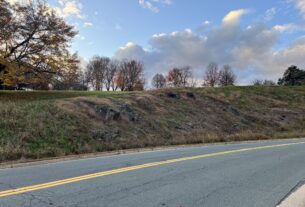 A hill with rocks showing through the grass beside the road at PVCC