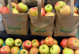 Three paper bags filled with apples behind pints boxes of apples