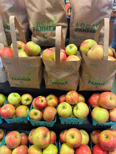 Three paper bags filled with apples behind pints boxes of apples