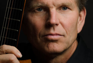 William Feasley poses holding his guitar.