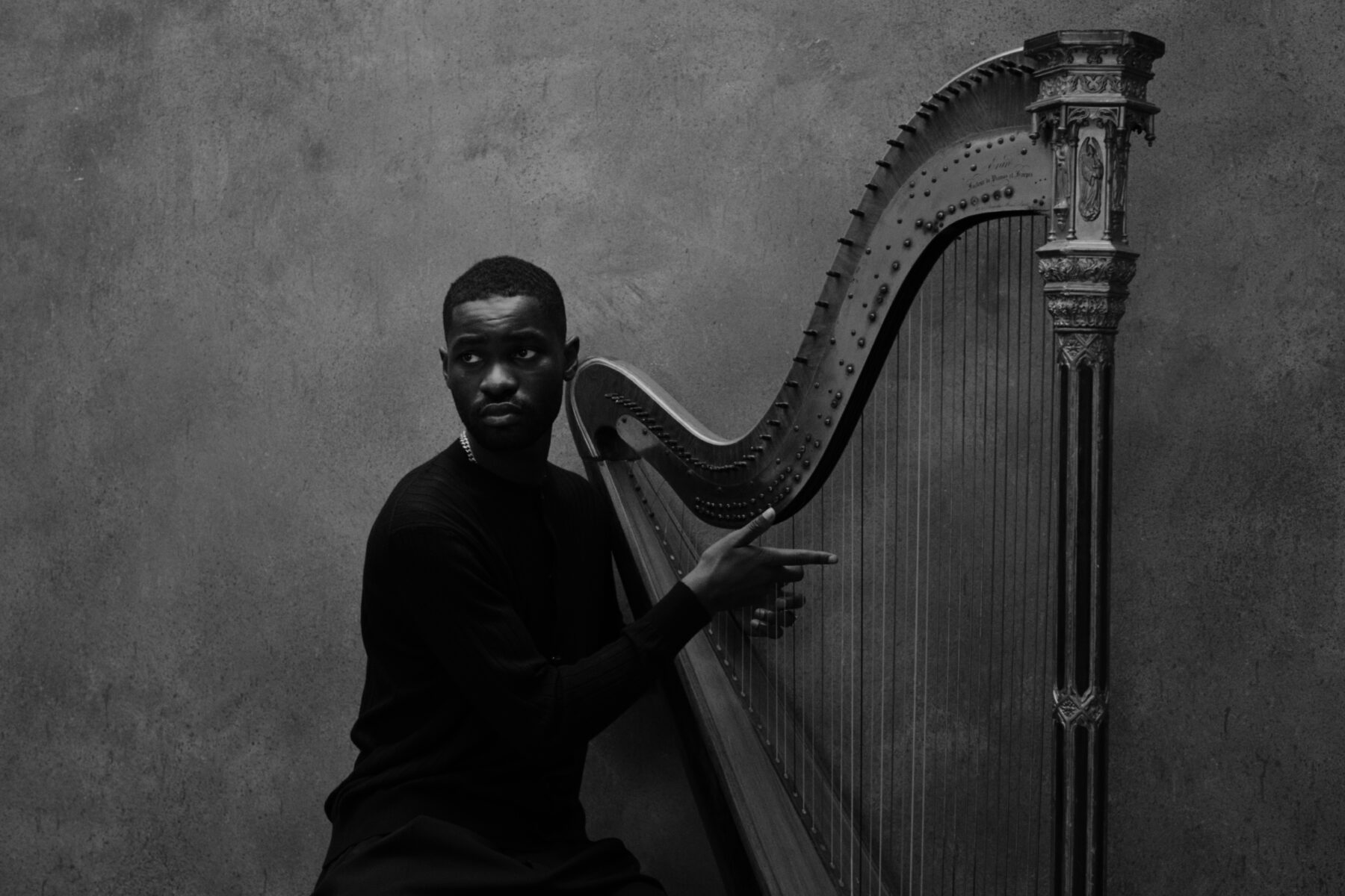 a black and white photo of Dave wearing a black shirt and posing with his harp