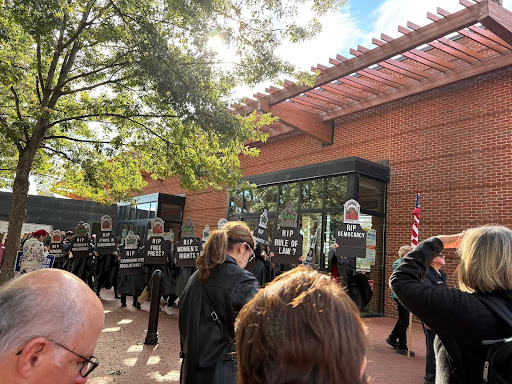 Protesters on the Downtown Mall holding black tombstones with white panted statements on them