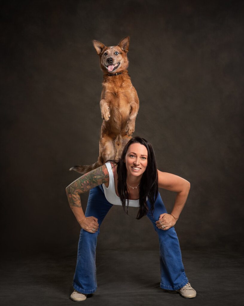 Jellybean the dog stands on its hind legs on a back of a crouching woman (Melissa Millett)