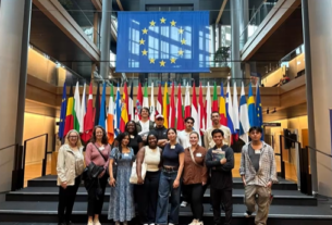 Students at the European Parliament in Strasbourg stand on steps in front of flags