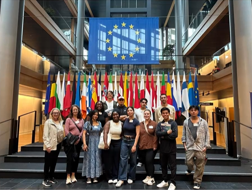 Students at the European Parliament in Strasbourg stand on steps in front of flags