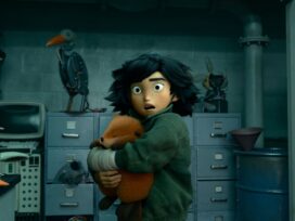 Mabel Tanaka hugging the robotic beaver to her chest in a lab with a shocked and confused expression on her face.