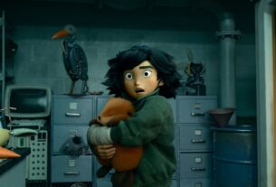 Mabel Tanaka hugging the robotic beaver to her chest in a lab with a shocked and confused expression on her face.