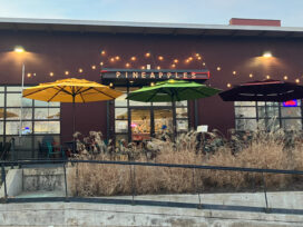 The exterior of a restaurant with yellow and green umbrellas outside.