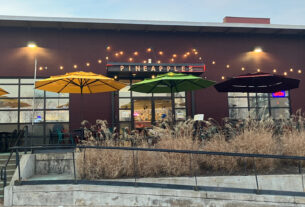 The exterior of a restaurant with yellow and green umbrellas outside.