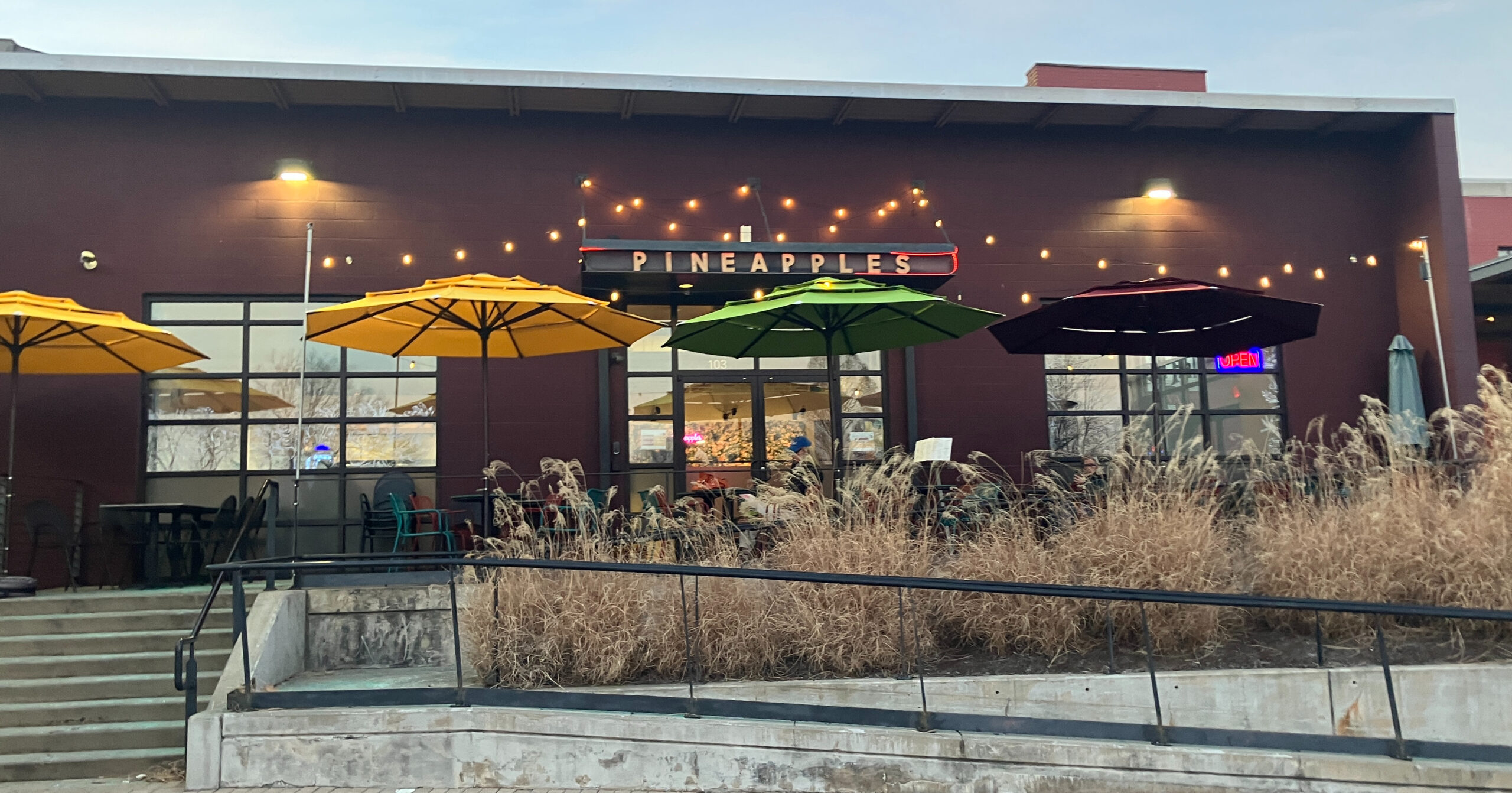 The exterior of a restaurant with yellow and green umbrellas outside.
