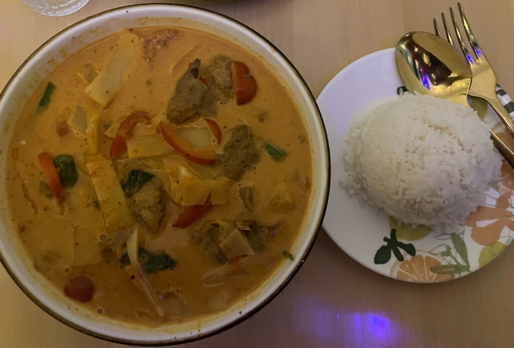 A bowl of yellow curry with vegetables and a smaller bowl of white rice.