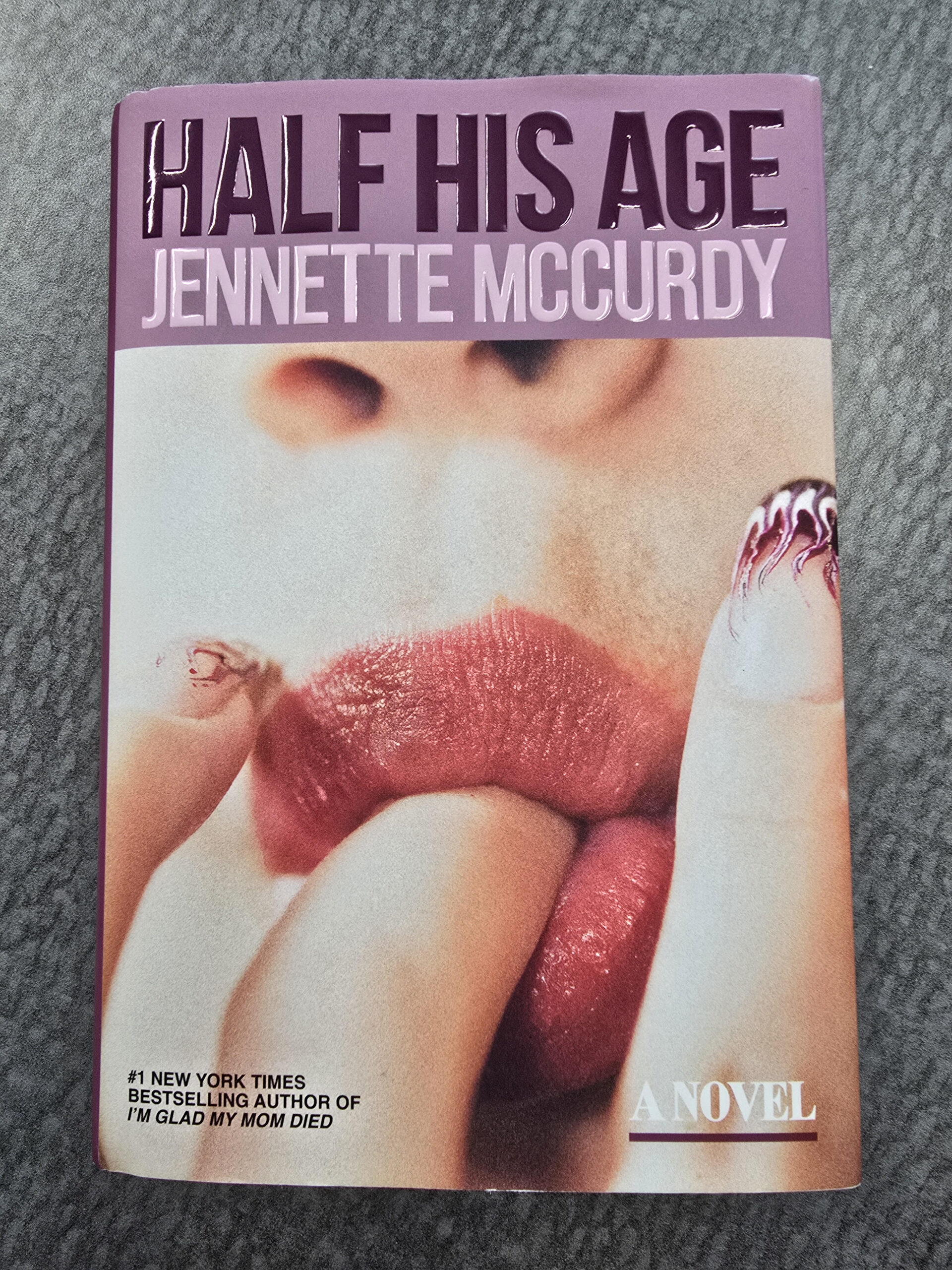 Book cover featuring close-up of a girl with painted nails sucking on her finger provactively.