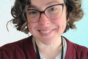 A headshot photo of Crystal Newell smiling and wearing a maroon color sweater.