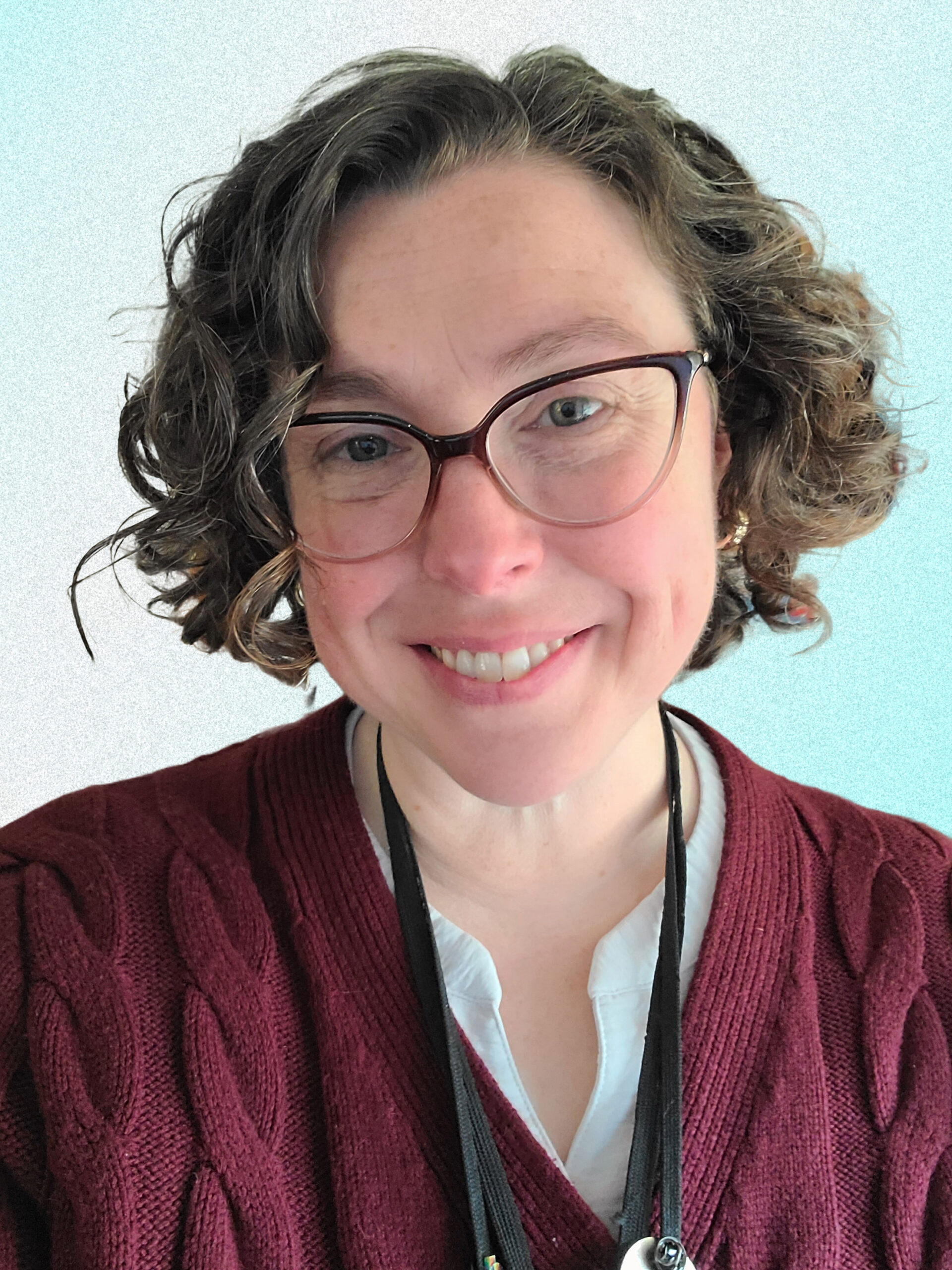 A headshot photo of Crystal Newell smiling and wearing a maroon color sweater.