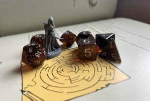 A set of seven tabletop role-play gaming dice ranging from four to 20 sides. They are sitting alongside a figurine on top of a maze on the page of an open book.