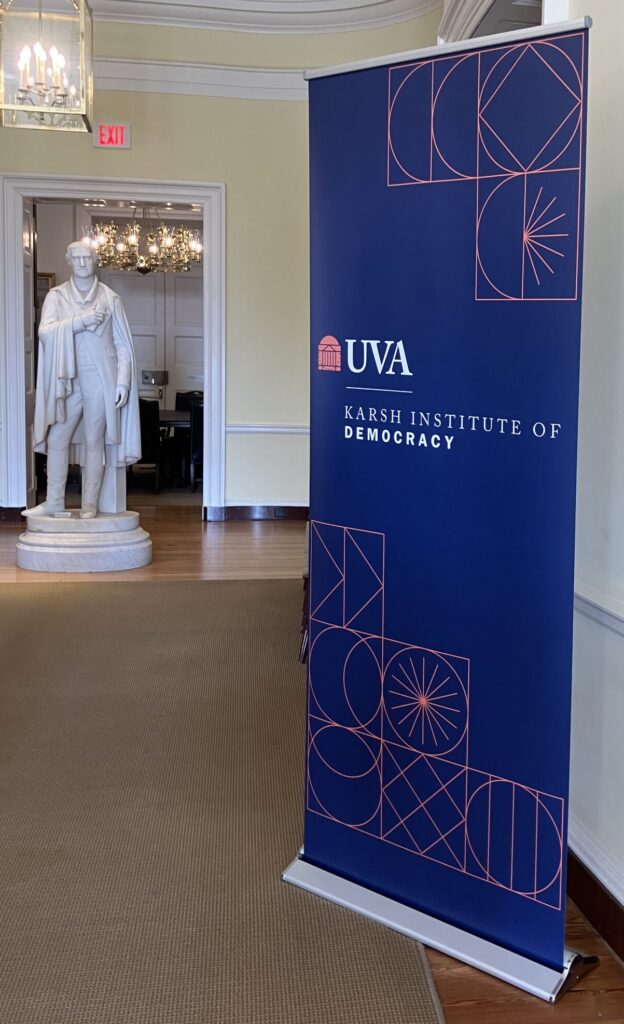 A white, marble statue of Thomas Jefferson next to a blue banner for the Karsh Institute of Democracy